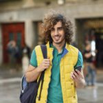 Spain, Granada, portrait of smiling young tourist with backpack discovering the city
